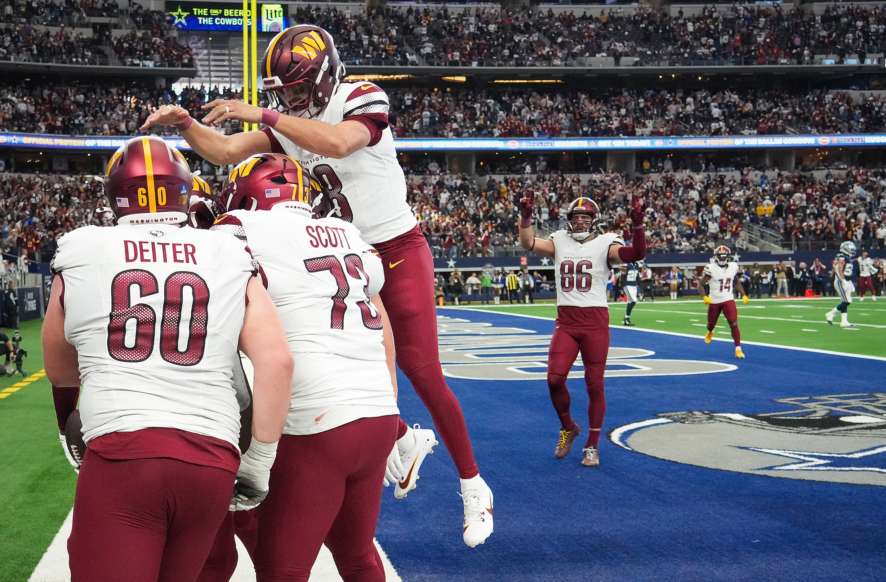 Washington Commanders quarterback Marcus Mariota (18) leaps into a celebration with guard...