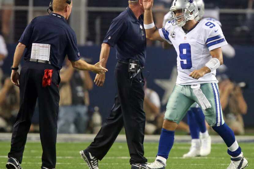 Dallas Cowboys quarterback Tony Romo (9) gets congratulated by head coach Jason Garrett...