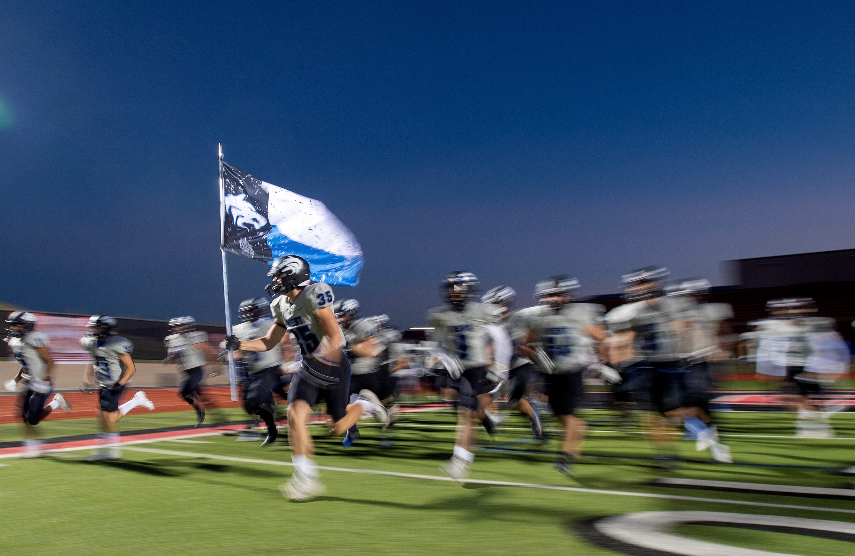 Plano West senior defensive end Cade Hathaway leads his team onto the field before a high...