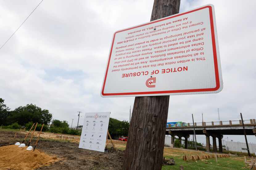 A city of Dallas notice of closure to homeless encampments hangs upside down from a utility...