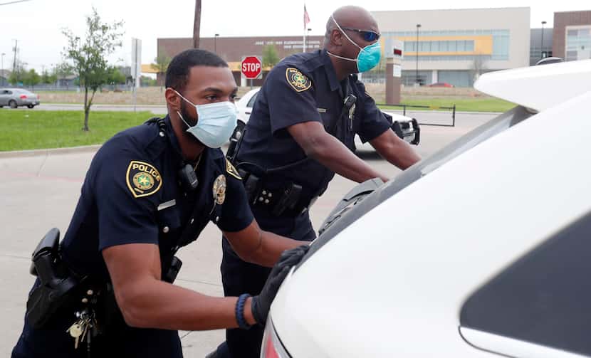 Dallas ISD police Officers Mylon Taylor (left) and Gary Pierre pushed a car that ran out of...