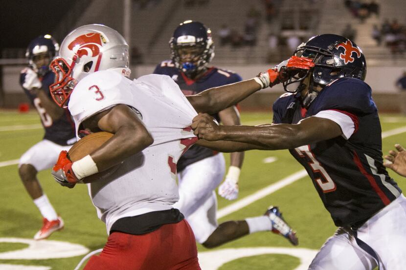 Kimball defensive back Tracy Davis (3) attempts to bring down Woodrow Wilson wide receiver...