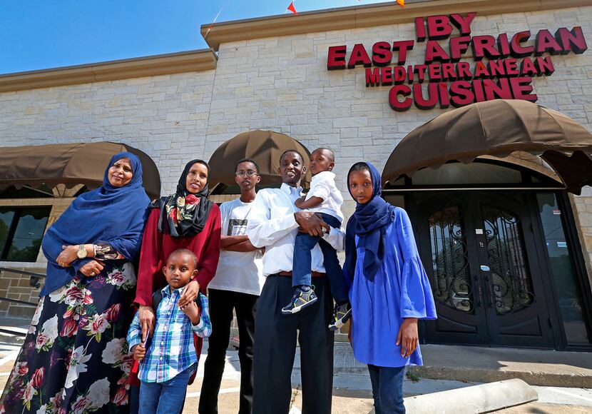 Abdulkadir Egal (second from right) holds his son Yusuf Egal, 2, in front of his restaurant...