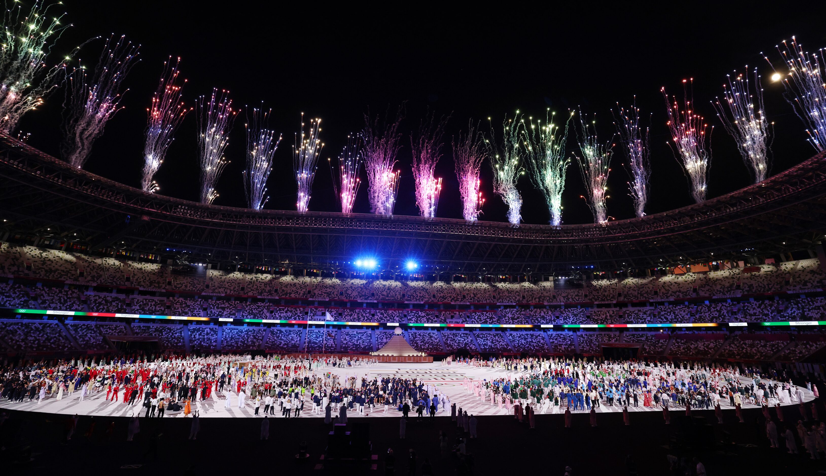 Fireworks go off as athletes watch after the introduction of the athletes during the opening...