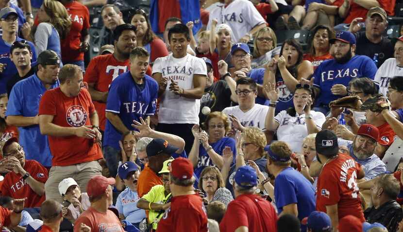 Baseball fans react as a foul ball hit by Texas Rangers left fielder Josh Hamilton (32)...