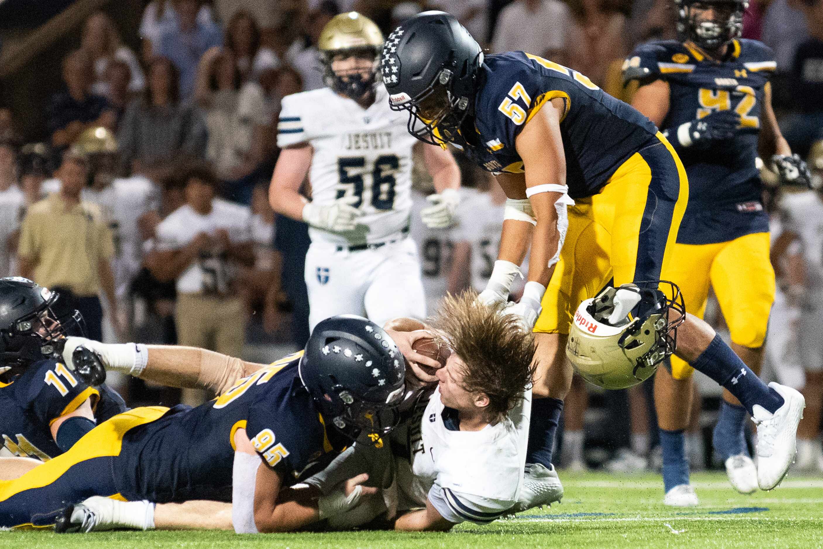 Jesuit senior quarterback Charlie Schmidt (17) loses his helmet as he's tackled after a run...