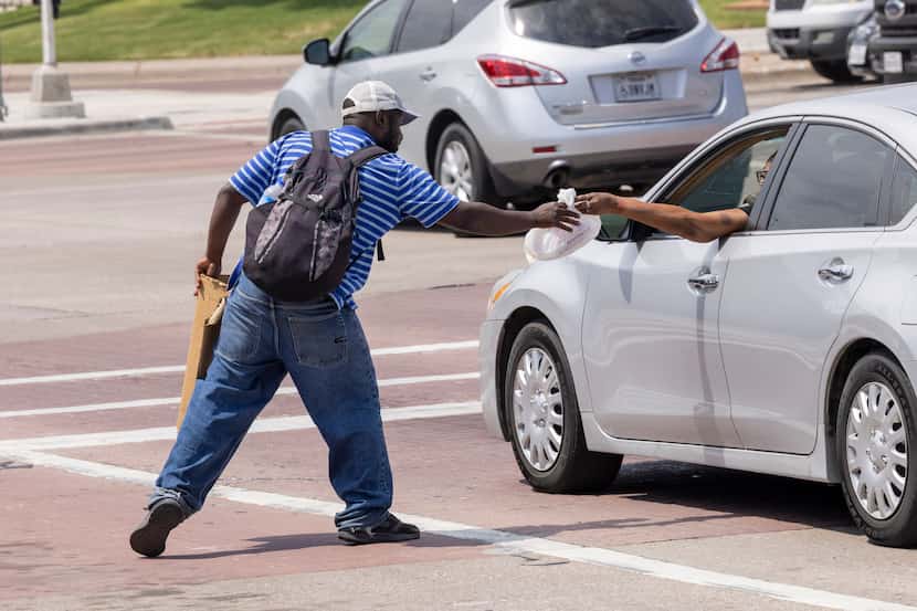A man accepts a bag of food from a driver in Dallas in June 2022.