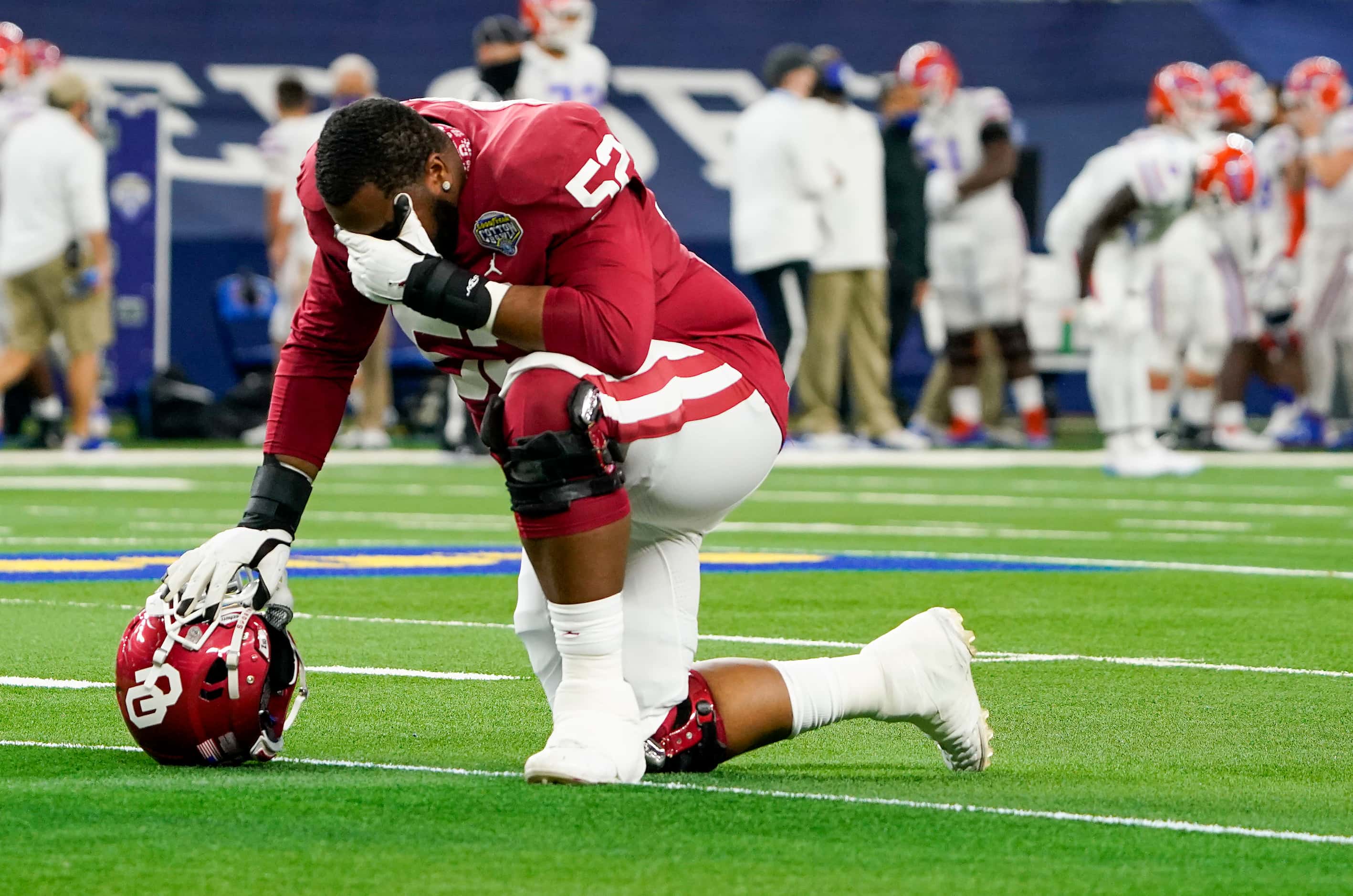 Oklahoma offensive lineman Tyrese Robinson (52) kneels in prayer before the Cotton Bowl...