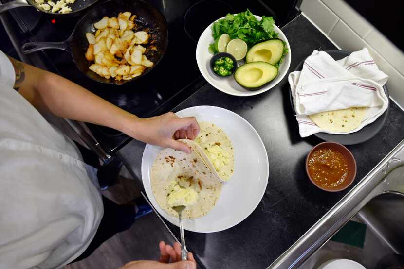 Chef Angela Hernandez places scrambled egg and potato on tortillas.