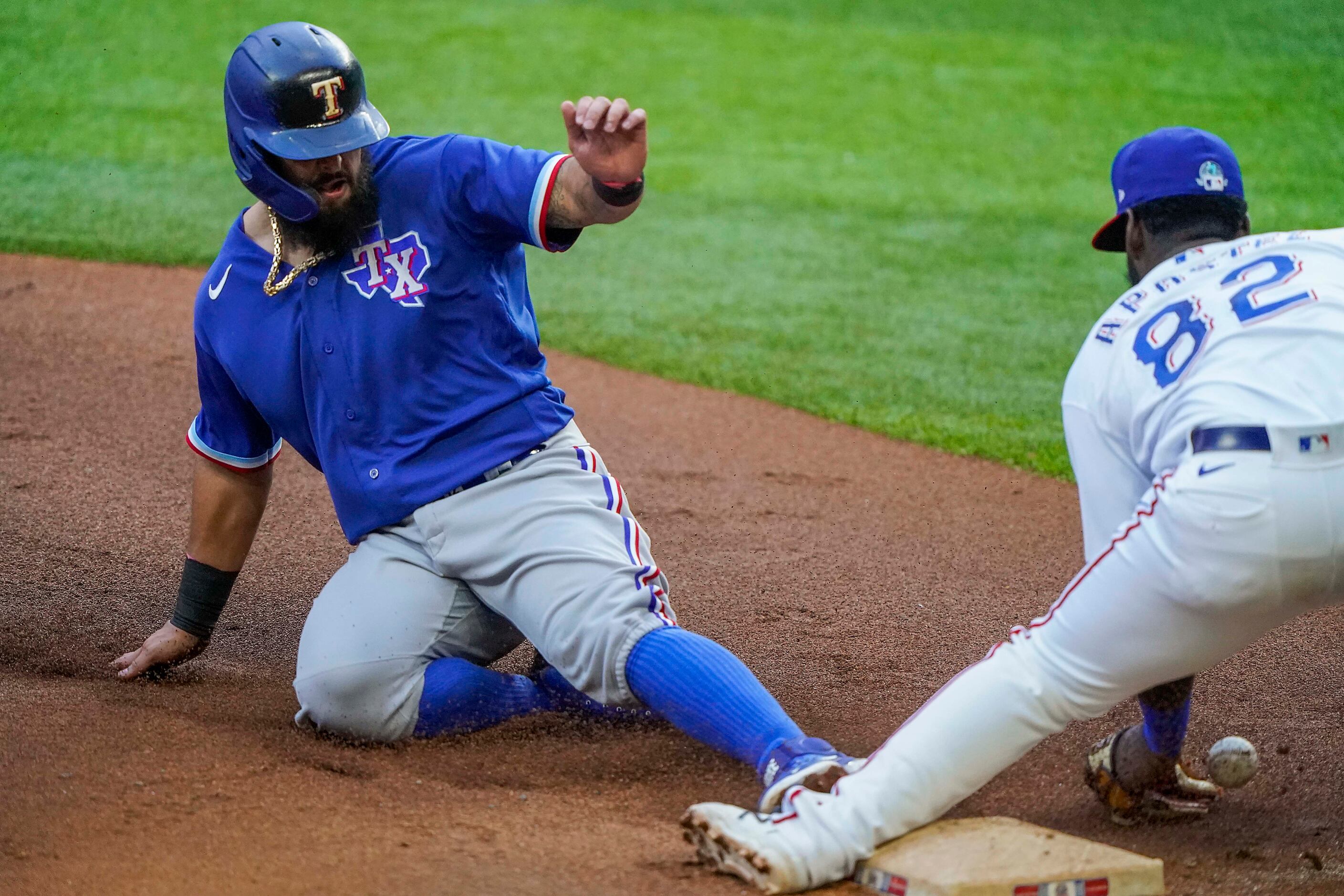Second baseman Rougned Odor is safe at third base with a steal as the ball gets away from...