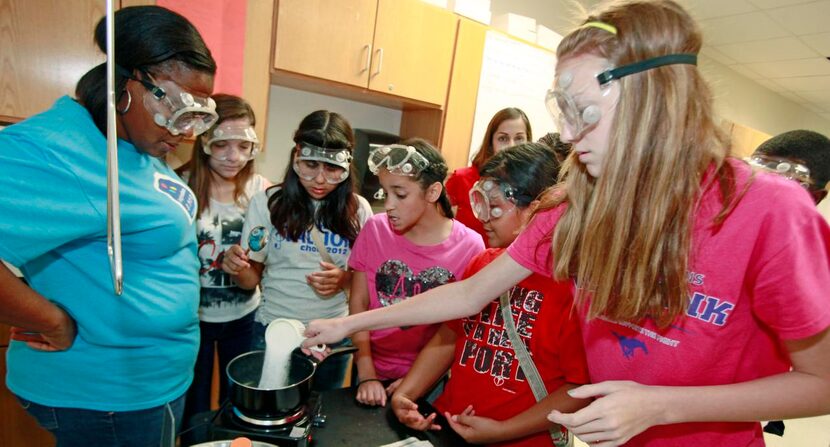 
Eighth grader Lena Cates, right, pours a cup of sugar into a pot of boiling water as her...