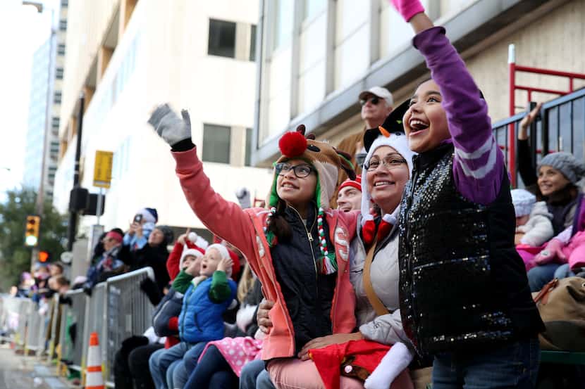 Triana Lopez (center), 9, waves to Santa Claus while sitting with her mother, Marisa Lopez...