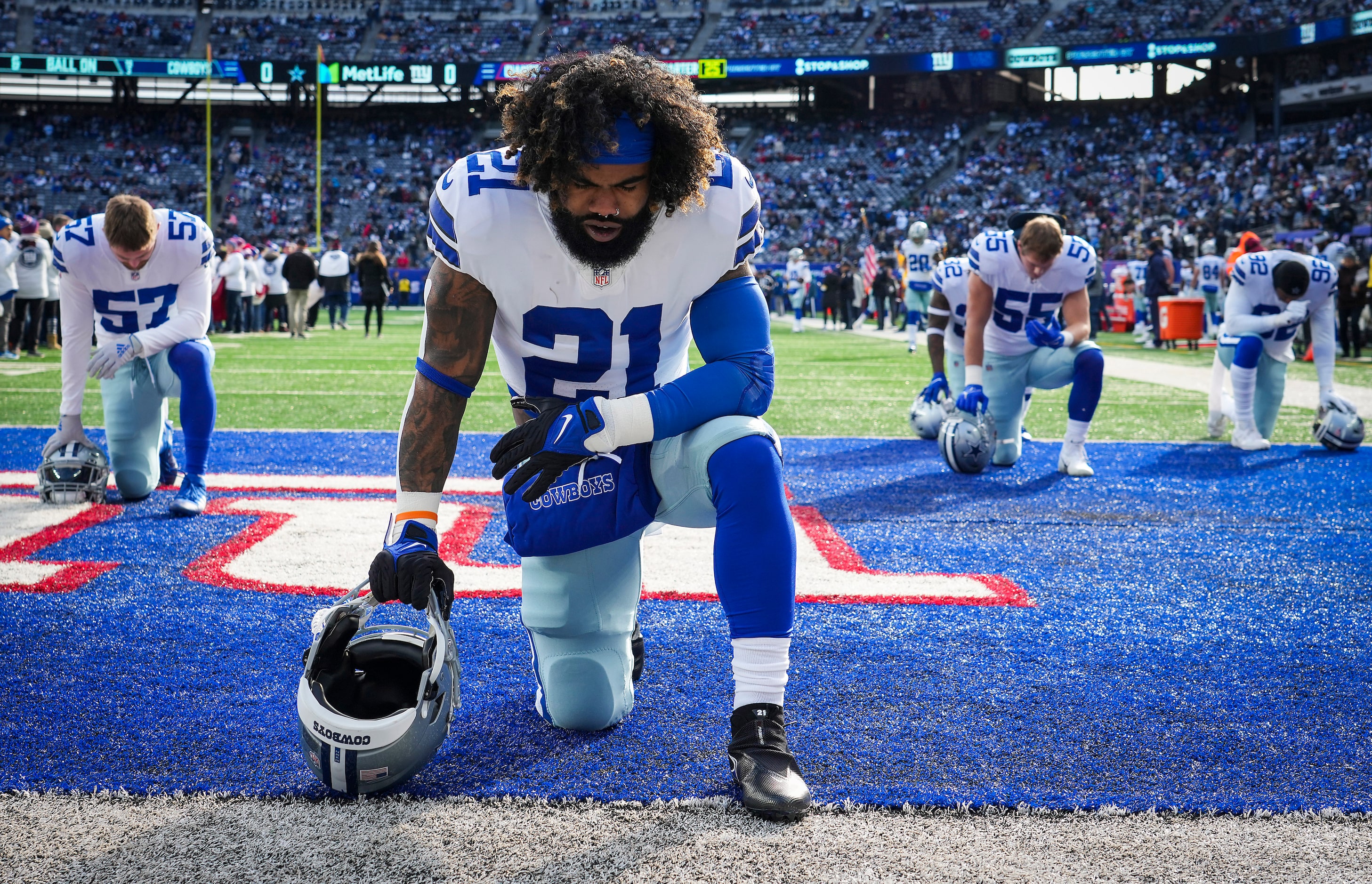 Dallas Cowboys running back Ezekiel Elliott knees on the field before the first half of an...