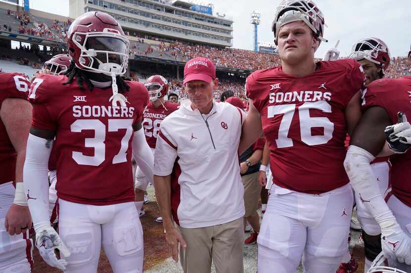Oklahoma head coach Brent Venables, center, leaves the field with players Justin Harrington...