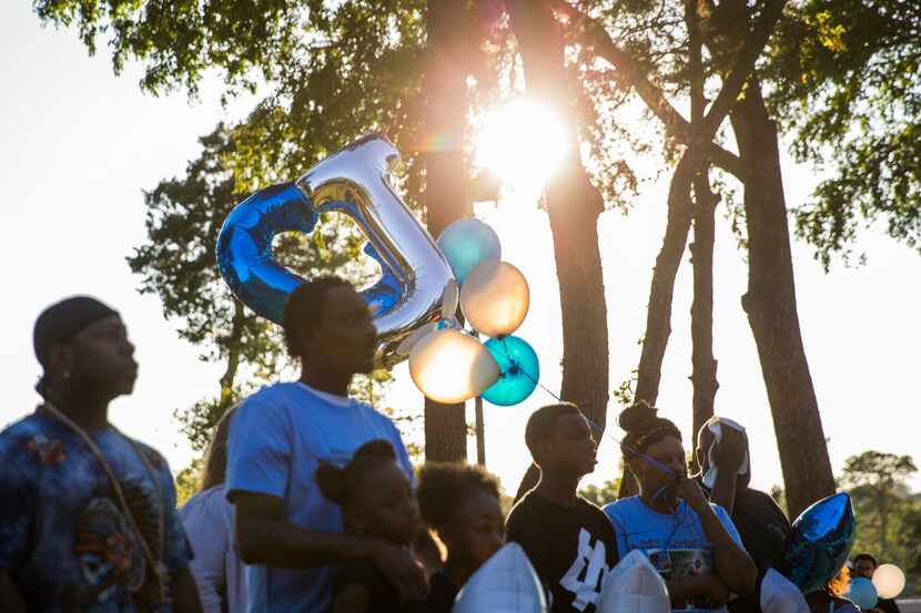 Friends and family members hold balloons during a vigil for 18-month-old Cedrick "C.J."...