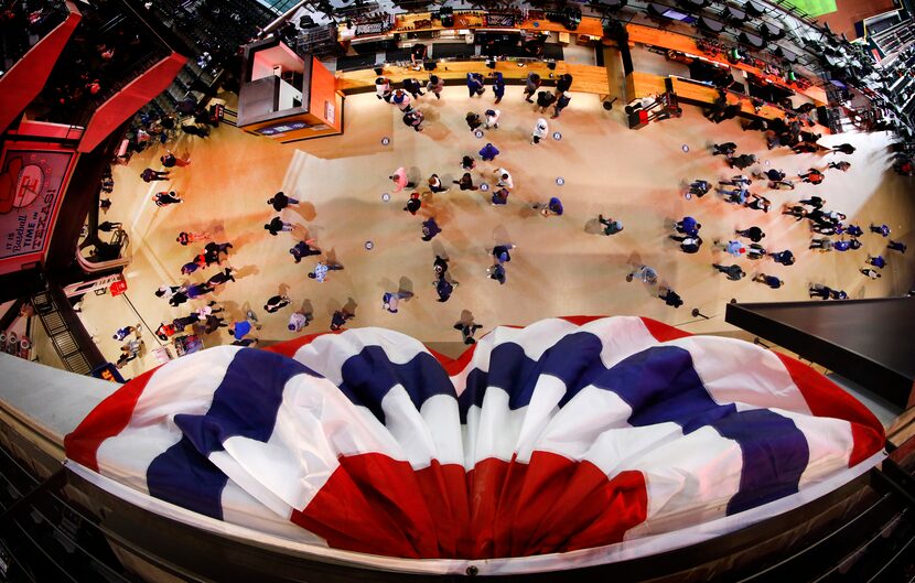 Baseball fans in the centerfield concourse walk below patriotic bunting before Game 3 of the...