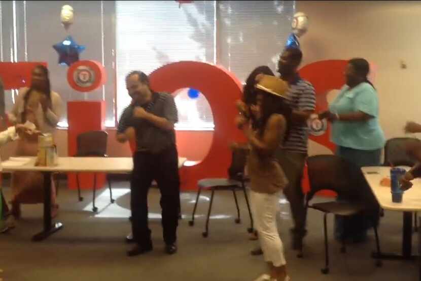 Frontier Communications staffers dance in their Irving office in front of a FiOS sign. A...