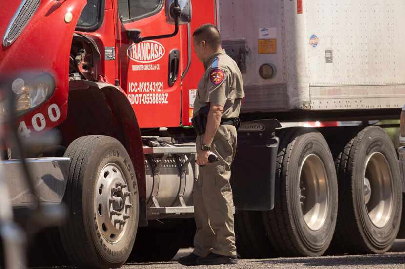 Un agente de Seguridad Pública de Texas inspecciona un camión en el control de...