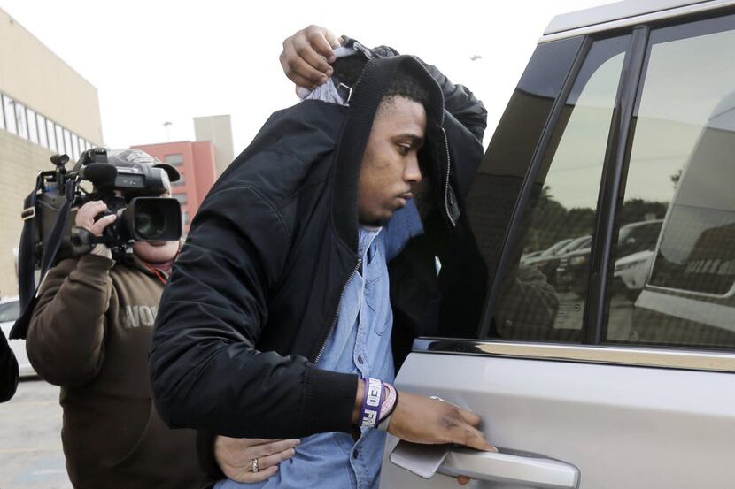 TCU quarterback Trevone Boykin holds a jacket over his head as he is escorted from a...