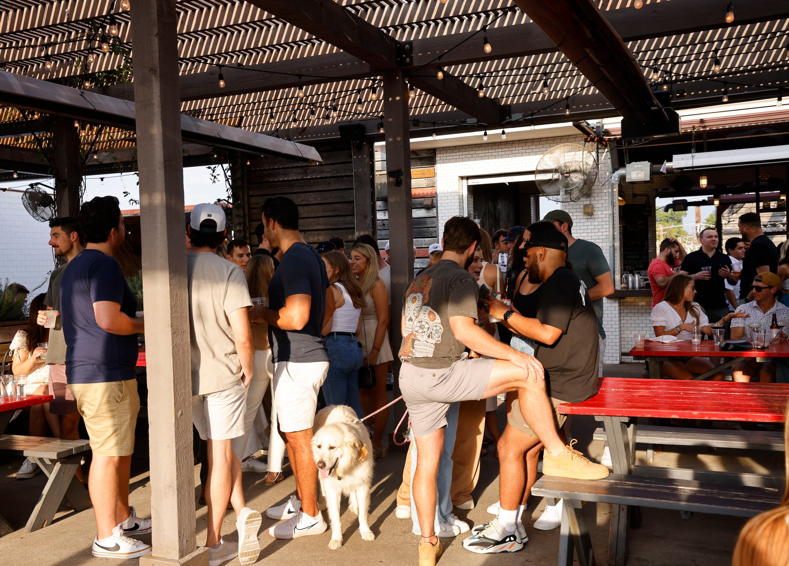 People gather on the patio at HG Sply Co. in the Lower Greenville neighborhood in Dallas,...