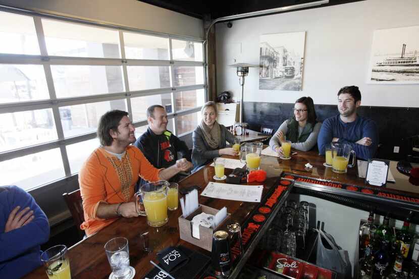 Chaps Tucker, 30, left, wearing a onesie, sits at the bar with friends drinking mimosa...