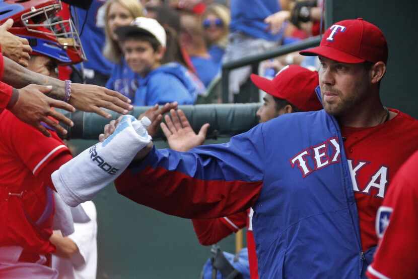 Texas pitcher Colby Lewis is greeted in the dugout by teammates during the Chicago White Sox...