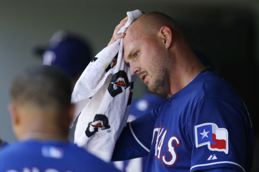 Texas Rangers starting pitcher Matt Harrison wipes his head in the dugout after the sixth...