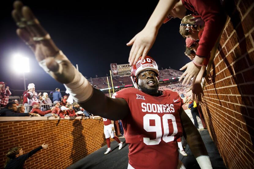 Oklahoma defensive tackle Neville Gallimore high fives fans after the Sooners 38-20 victory...