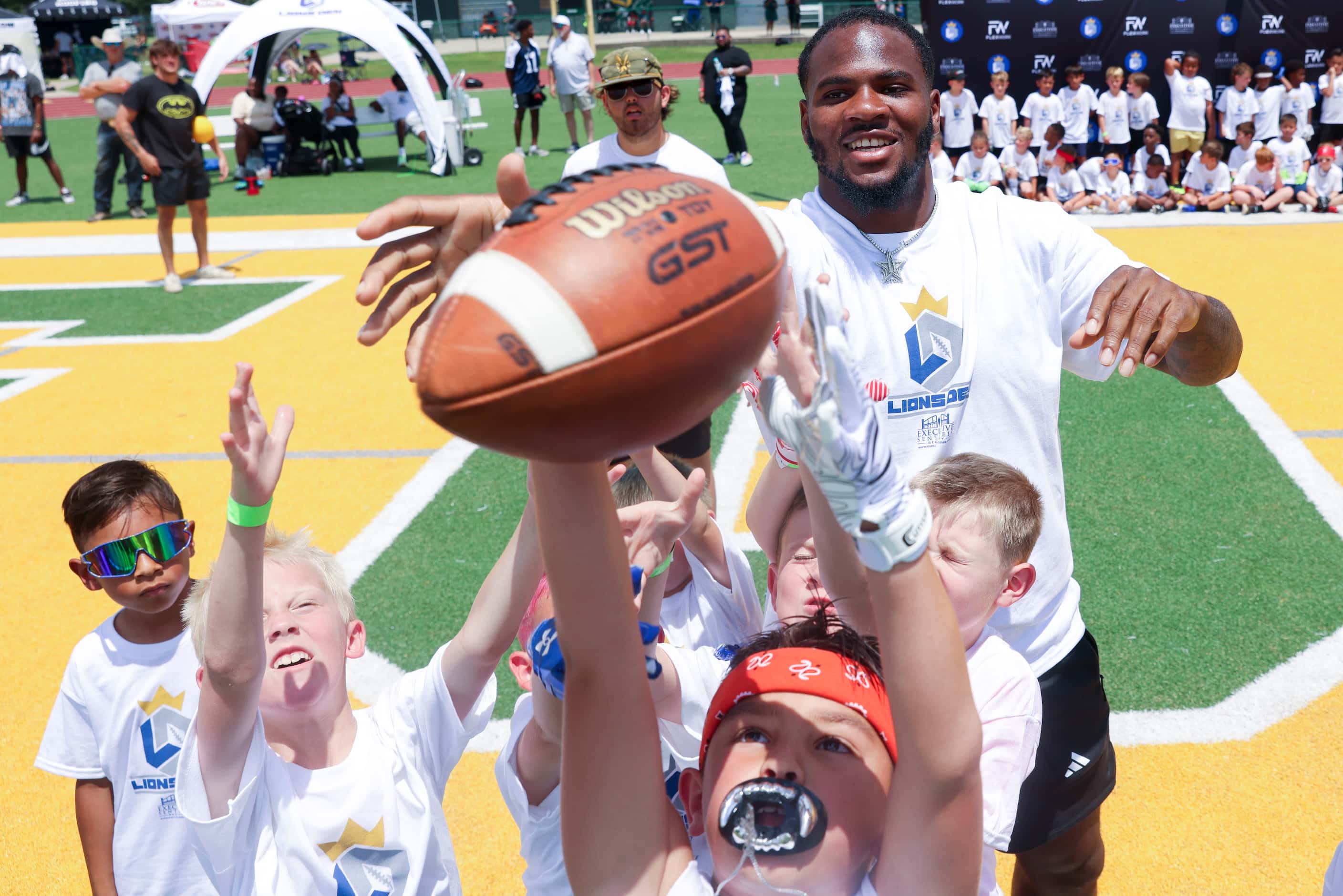 Dallas Cowboys linebacker Micah Parsons receives a pass as he interacts with young football...