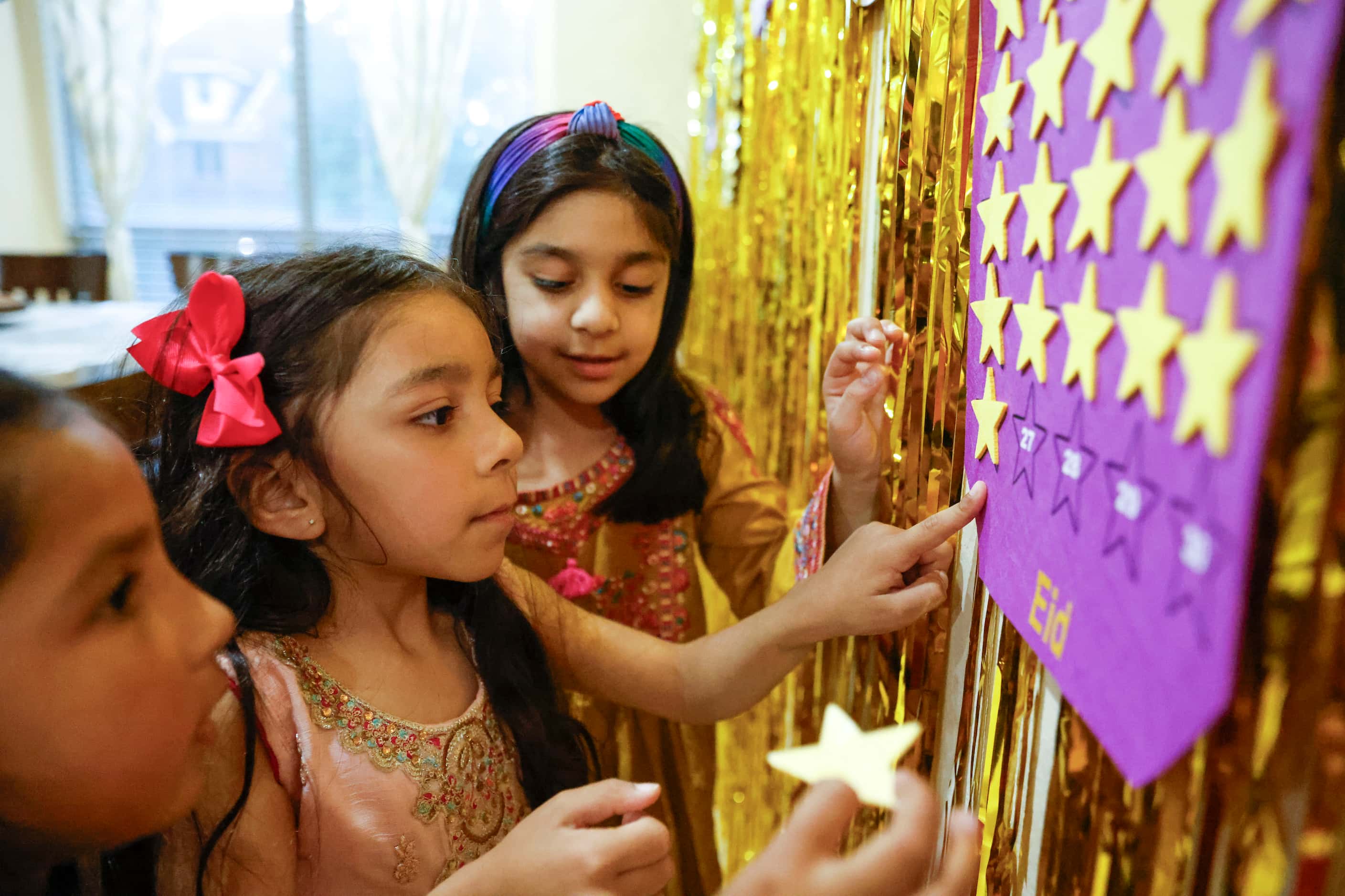 Aizah Choudhry, 6, (back), her sister Aleena, 4, (center), and friend Mahira Fazal, 5, puts...