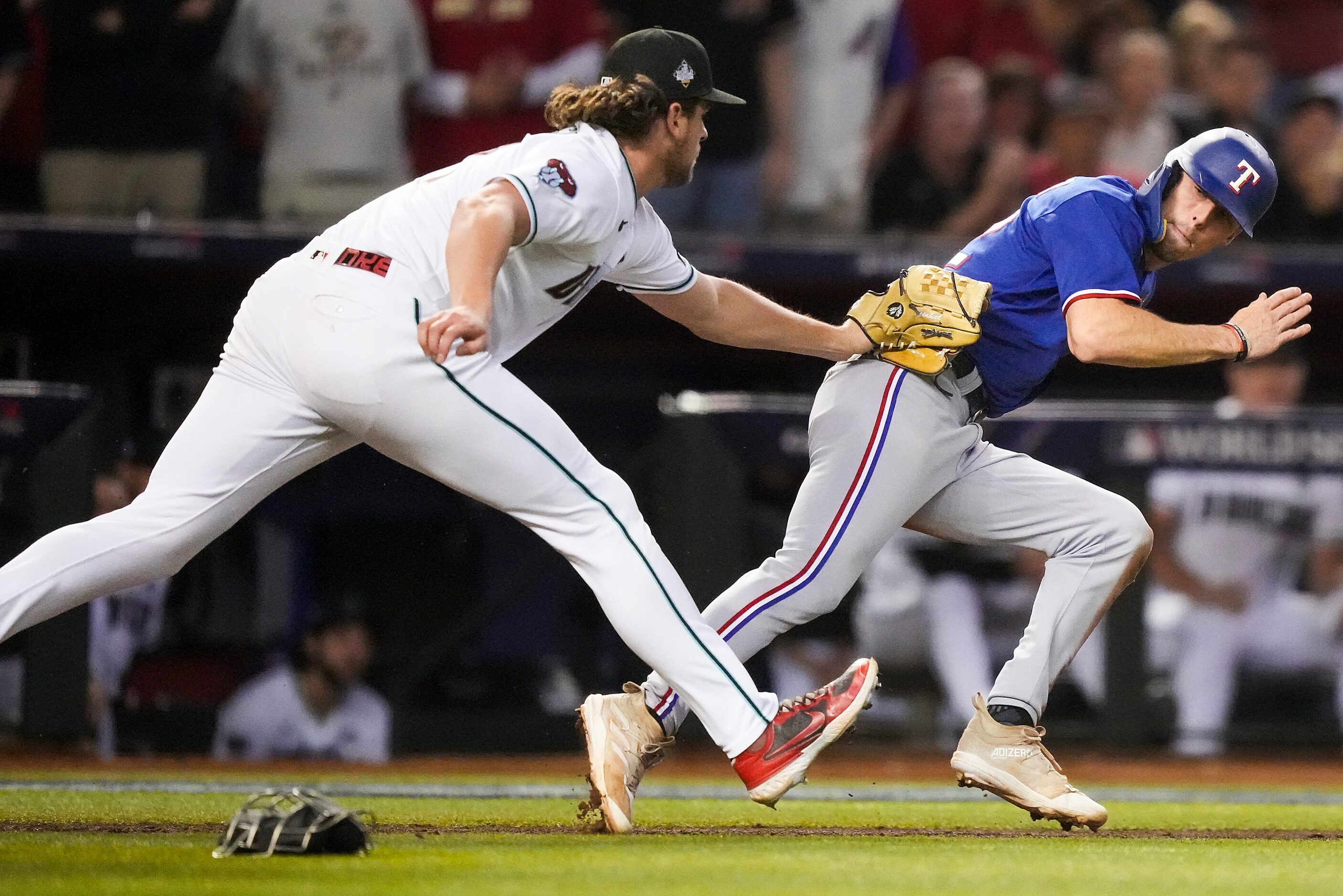 Arizona Diamondbacks relief pitcher Kevin Ginkel tags out Texas Rangers Evan Carter in a run...