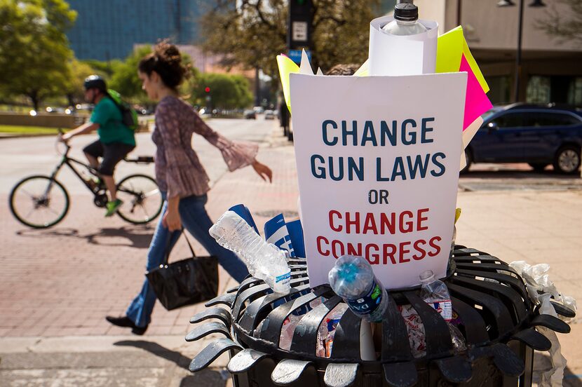 Protest signs and water bottles fill a sidewalk trash bin after a rally and march in support...