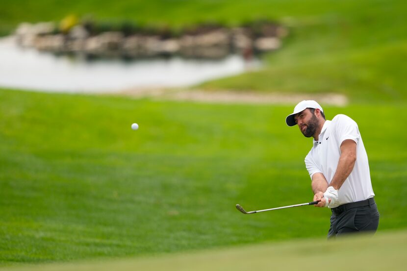 Scottie Scheffler chips to the green on the 18th hole during a practice round for the PGA...