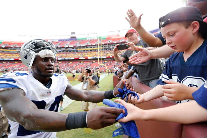 Dallas Cowboys cornerback Morris Claiborne (24) hands over his gloves to a fan after the...