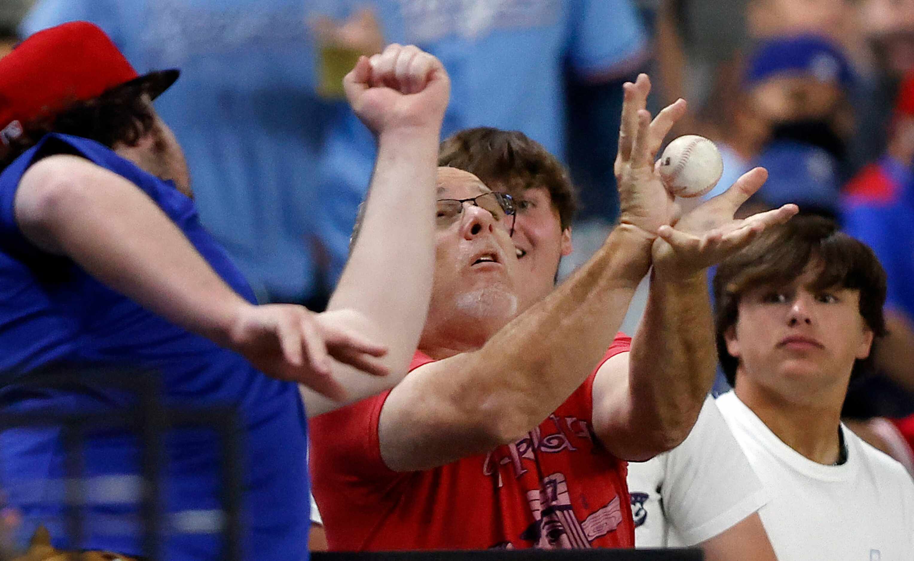 A Texas Rangers fan tries to catch a Los Angeles Angels foul ball during the third inning at...