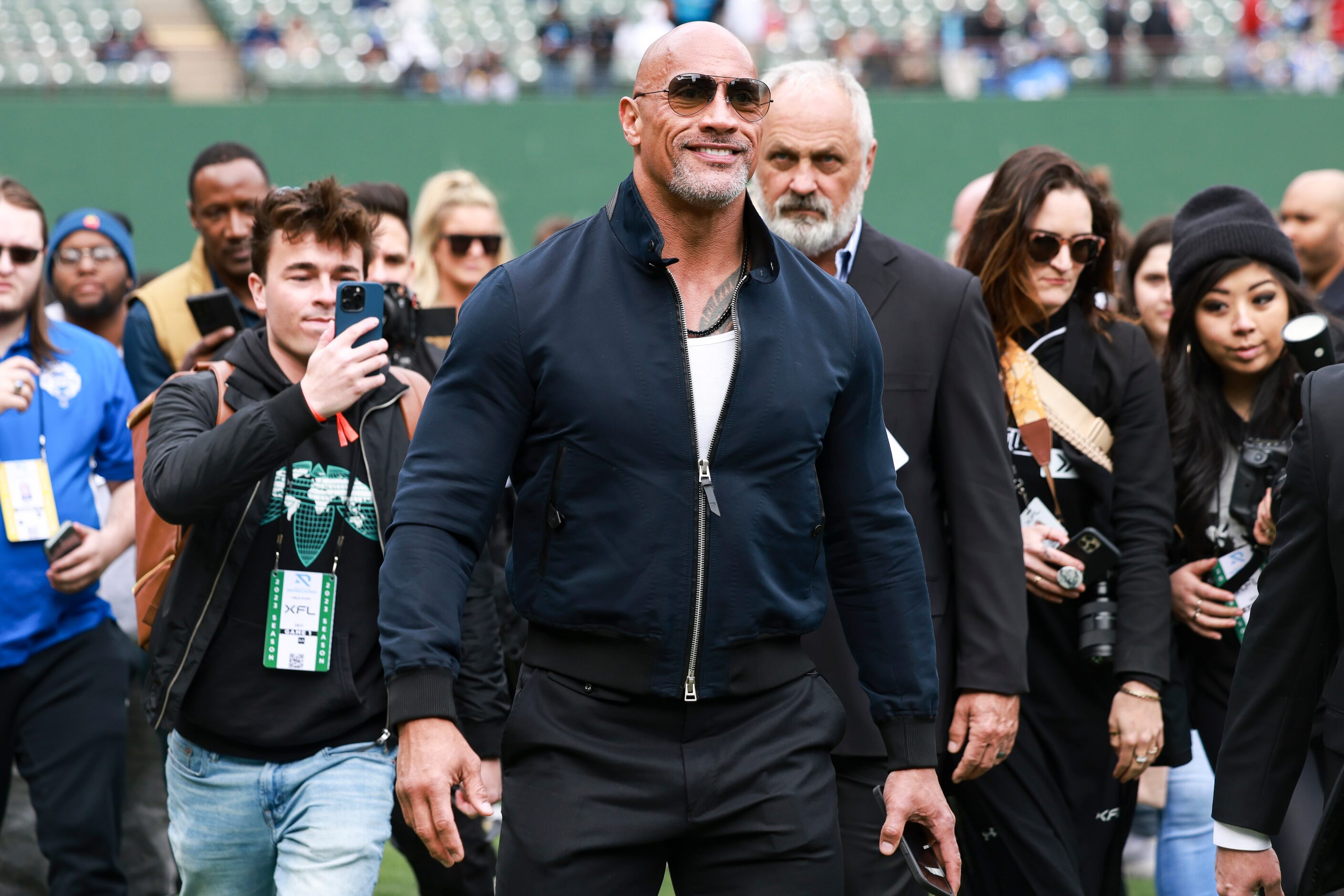 Dwayne “The Rock” Johnson walks on the field’s sidelines before an XFL football game between...