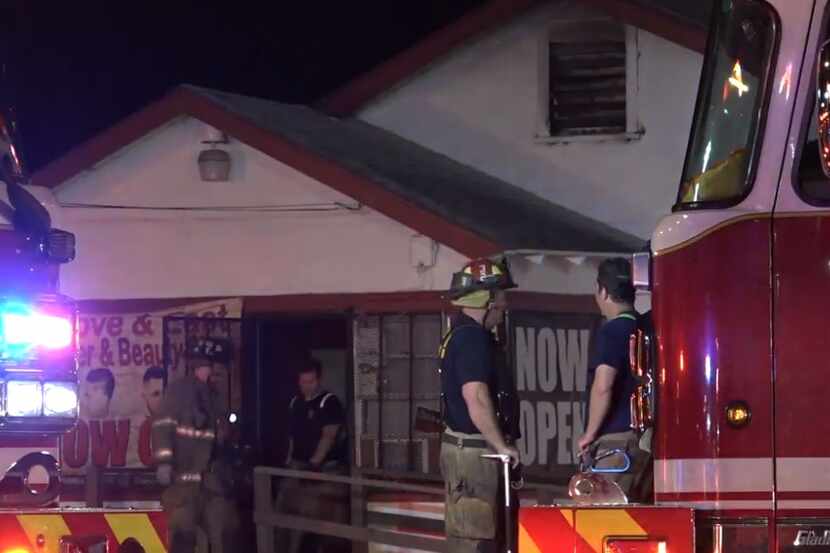 Firefighters emerge from a business heavily damaged by fire Tuesday morning in far east Dallas.