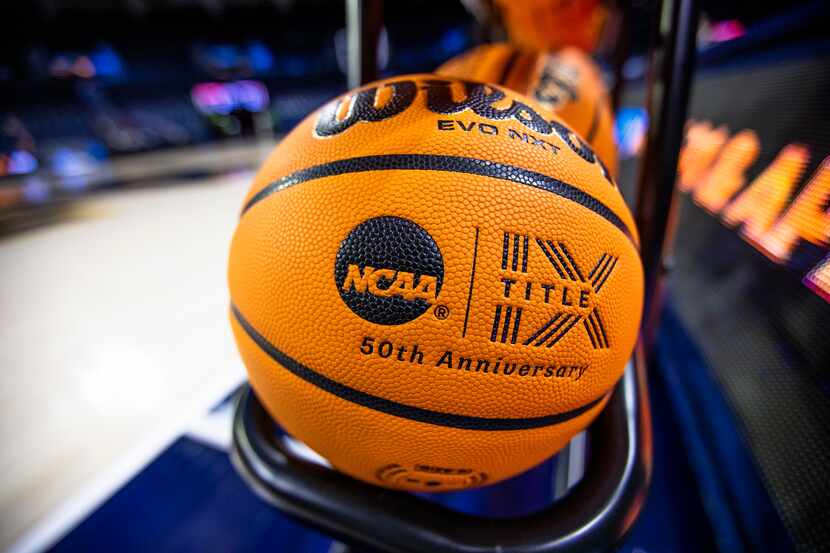 FILE- A basketball with an NCAA logo and a Title IX inscription rests on a rack before a...