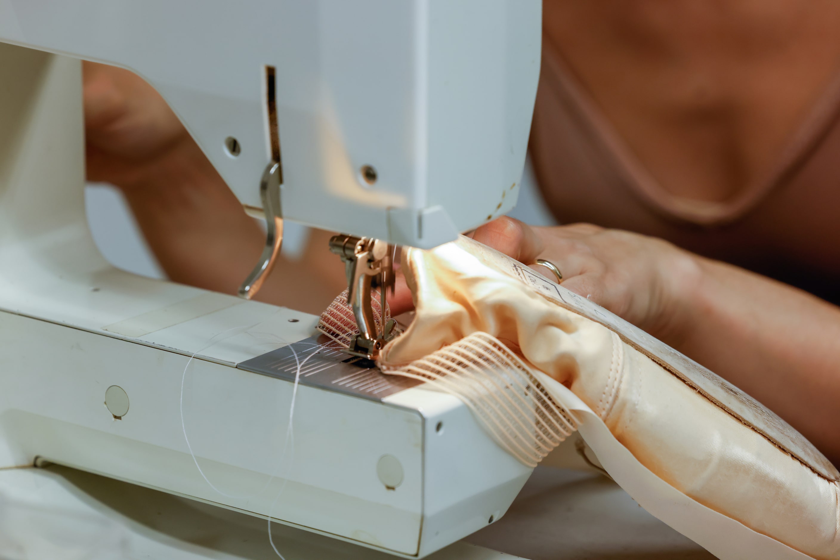 Alexandra F. Light (Alice) adds stitches to the bands on her pointe shoes before a dress...