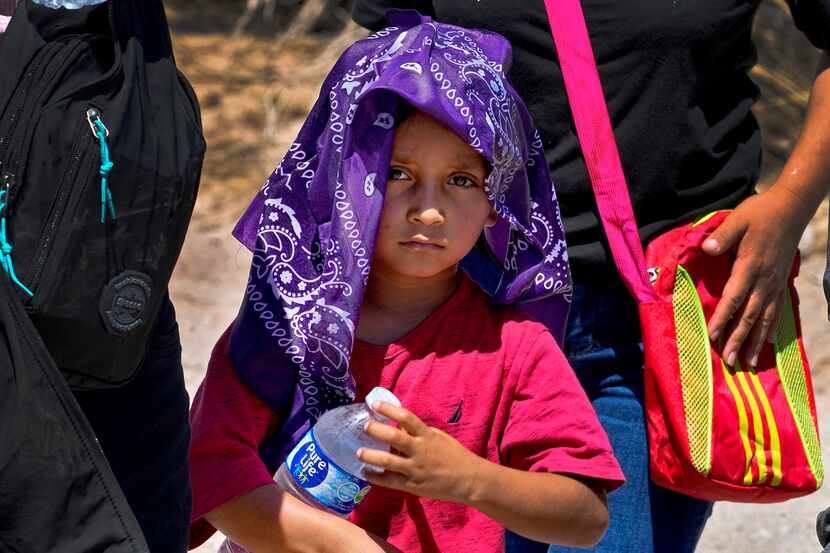 A young child and his mother, claiming to be from Guatemala, cools down with a wet bandana...