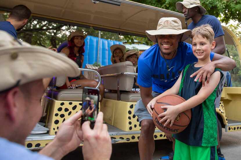 Dallas Mavericks fan Noah Price, 8, poses for a photograph with player Dennis Smith Jr....