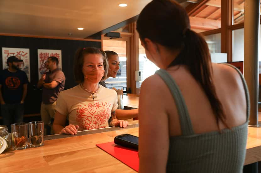 Loro bartender Demitria Lowe presents drinks from an order to guest Michelle Peterson from...