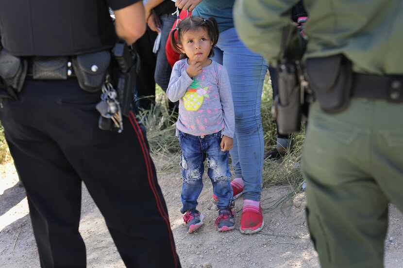 A Mission police officer and a U.S. Border Patrol agent watch over a group of Central...