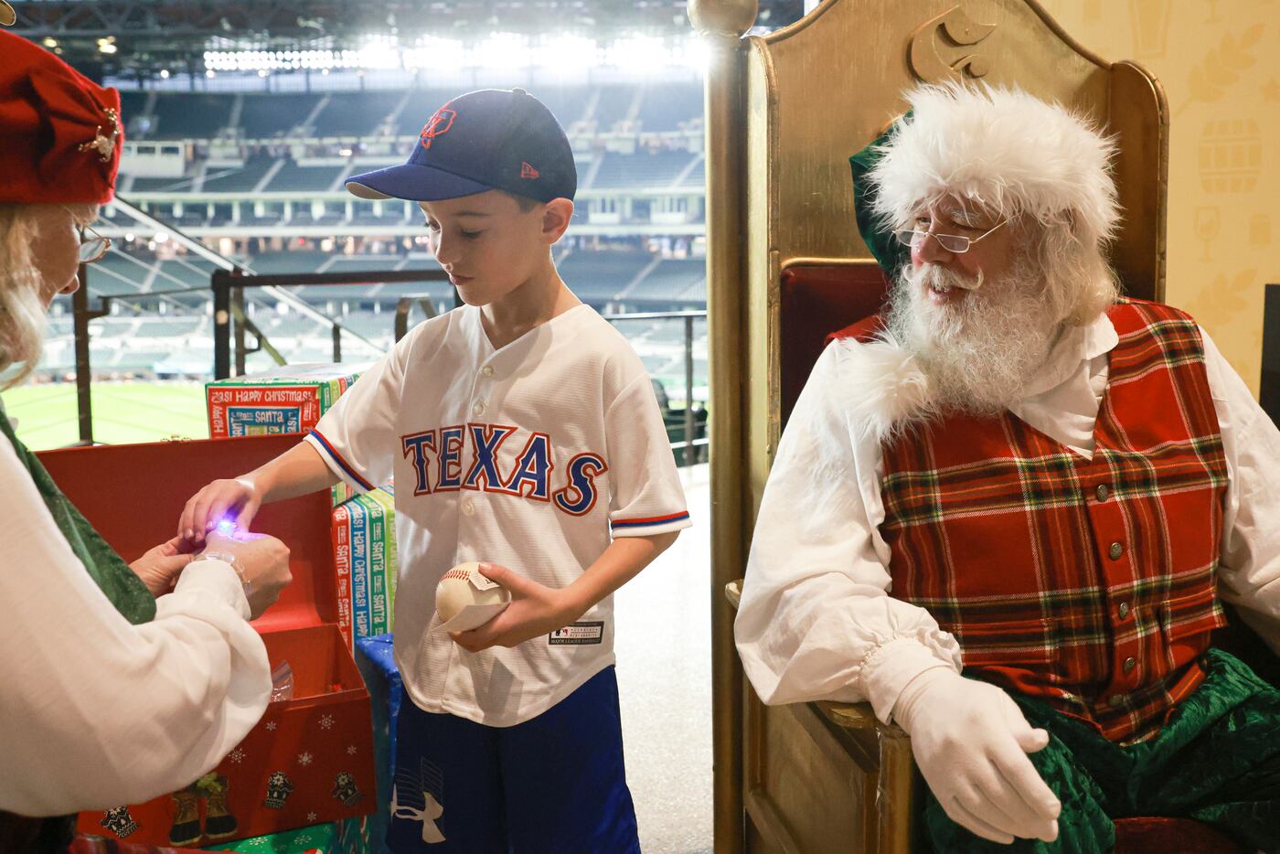 Camden James, 7, takes a light up toy from Mrs. Claus at Globe Life Field, Monday, Dec. 12,...