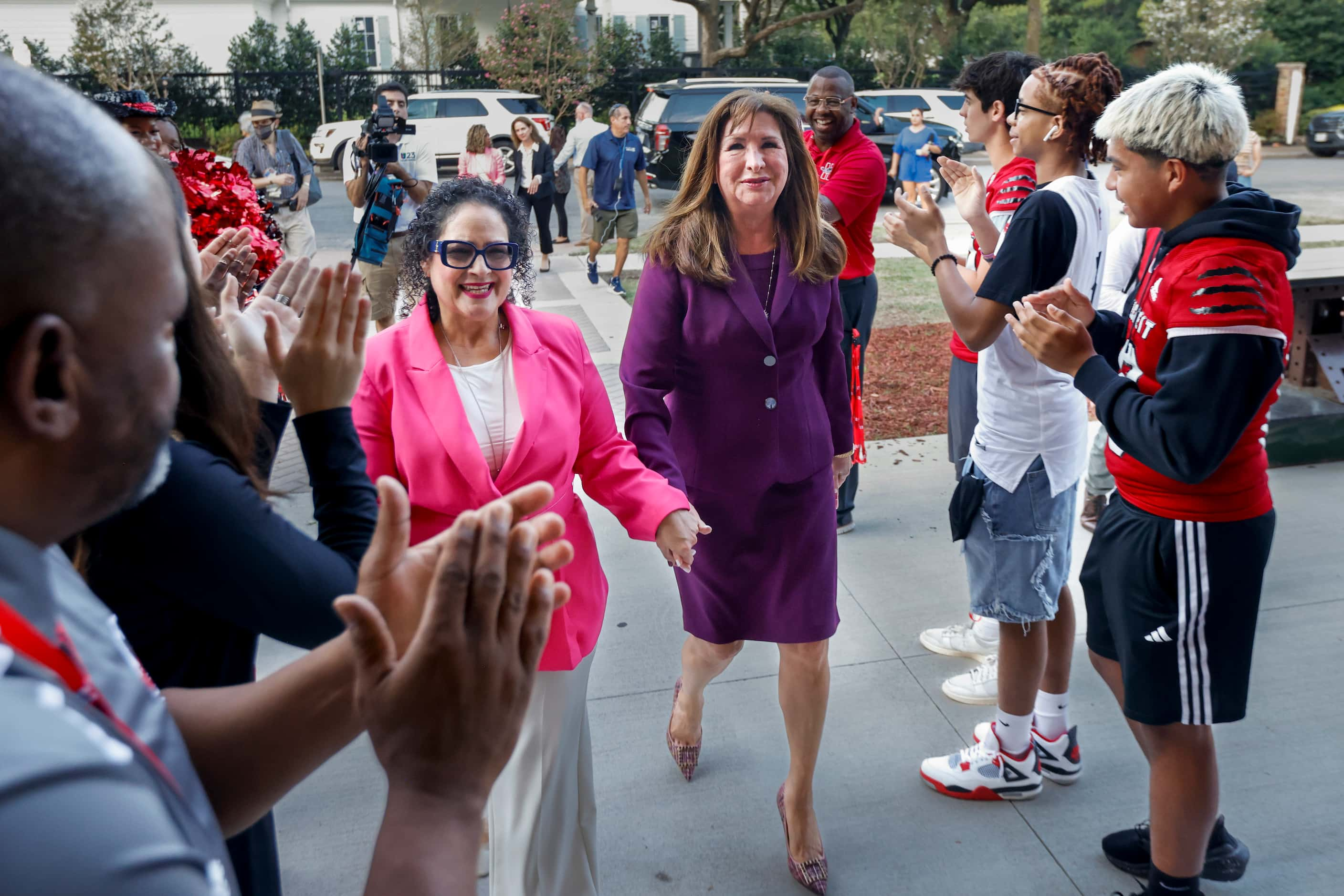 John J. Pershing Elementary School principal Lourdes Morales-Figueroa (left) walks hand in...