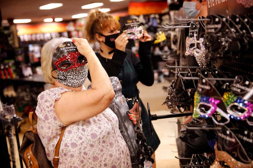 Sandy Staten tries on a costume mask to go with her COVID mask during a shopping trip to...