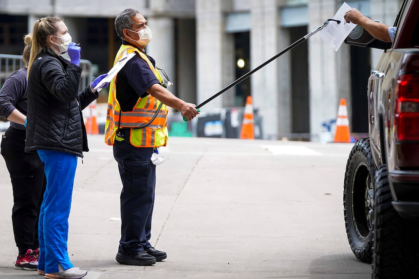 Health-care workers used a gripper tool to give paperwork to a person being screened at a...