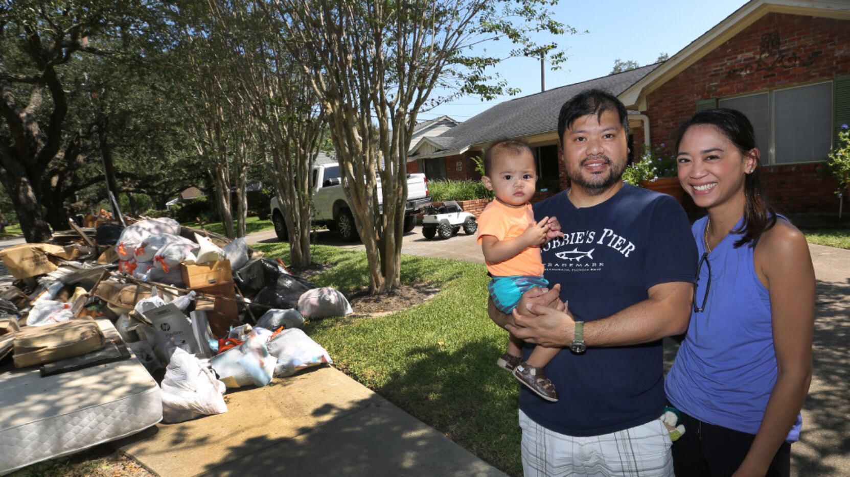 Troy and Catherine Pham and 13-month-old Aidan outside their flood-damaged home in the...