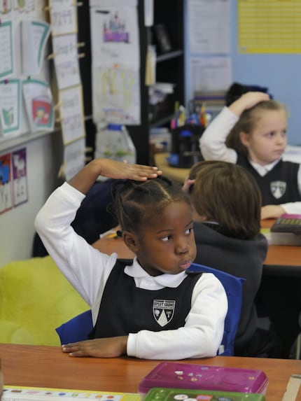 Uplift Grand Preparatory first-grader Mefowe Kue, 6, pats her head to signal agreement with...