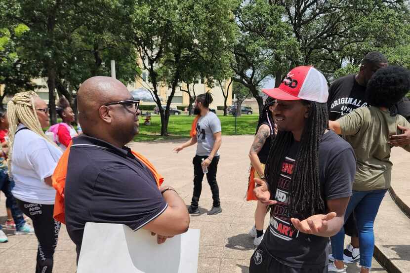 Rodney Thomas (left) speaks to a gun violence rally attendee at Dallas City Hall in summer...